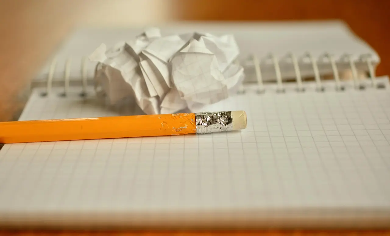 Notes w kratkę i ołówek obok zmiętej kartki na biurku